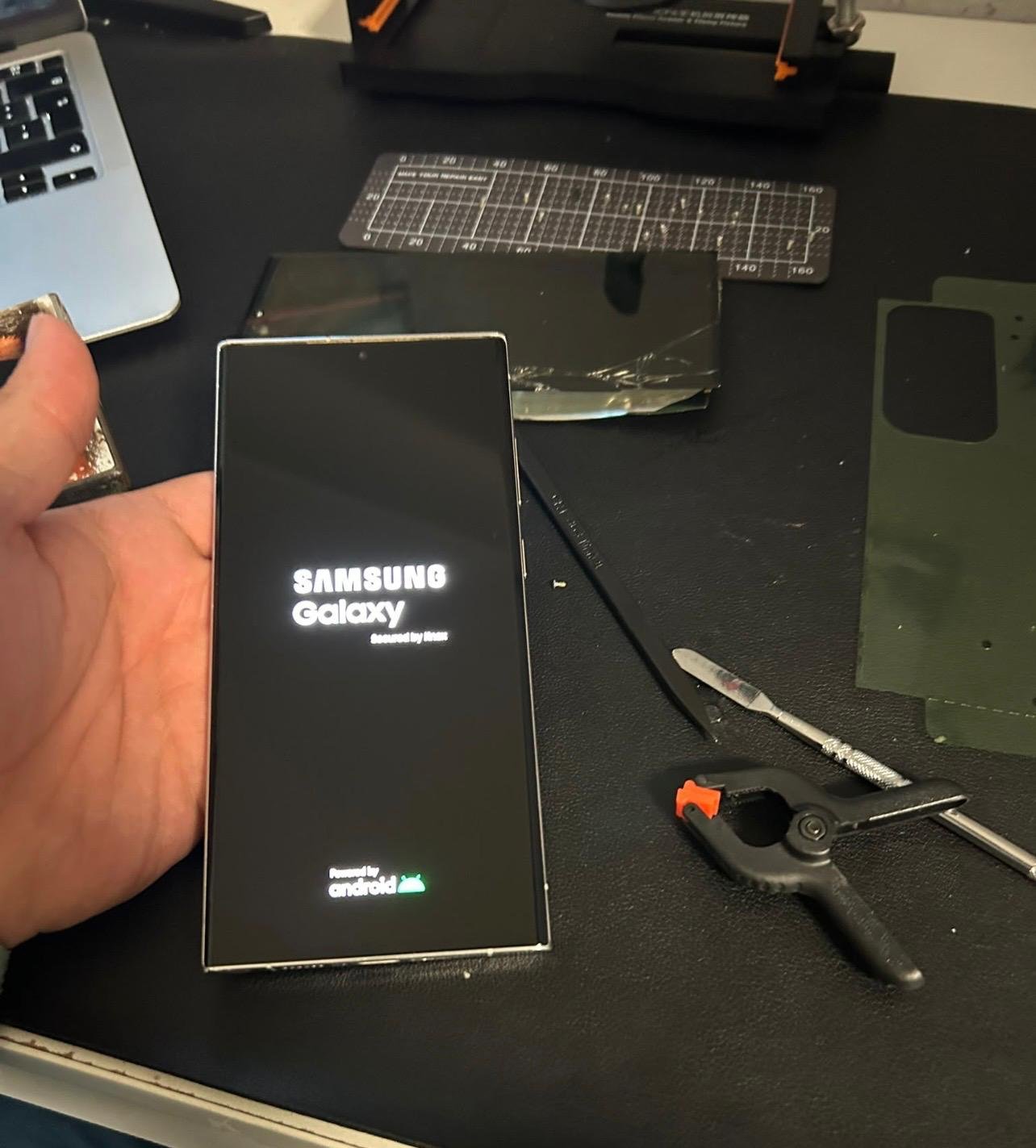 Samsung Galaxy beim Start mit ausgebautem Display im Hintergrund