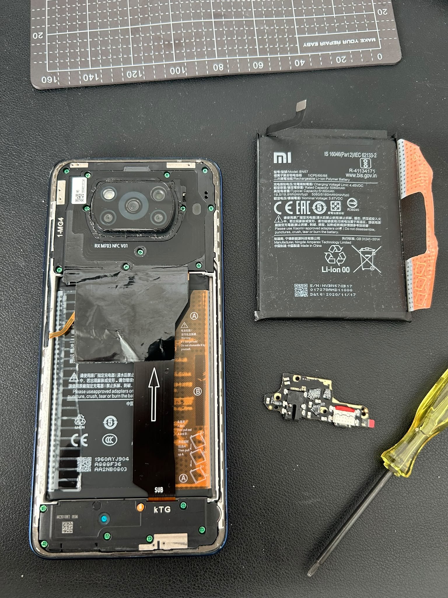Geöffnetes Smartphone mit Akku und Ersatzteilen am Reparaturplatz