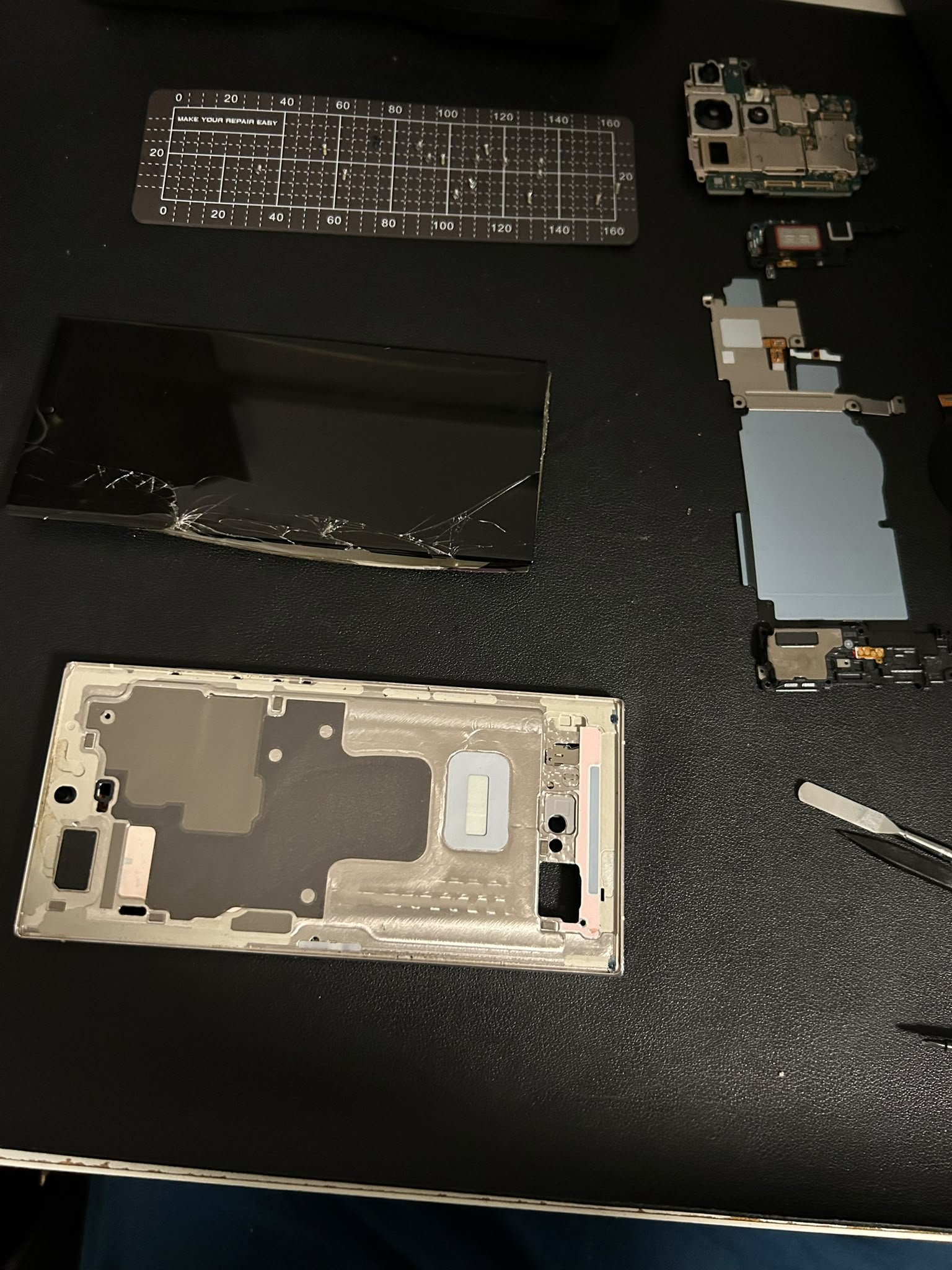 Smartphone-Display und Bauteile auf dem Reparaturplatz